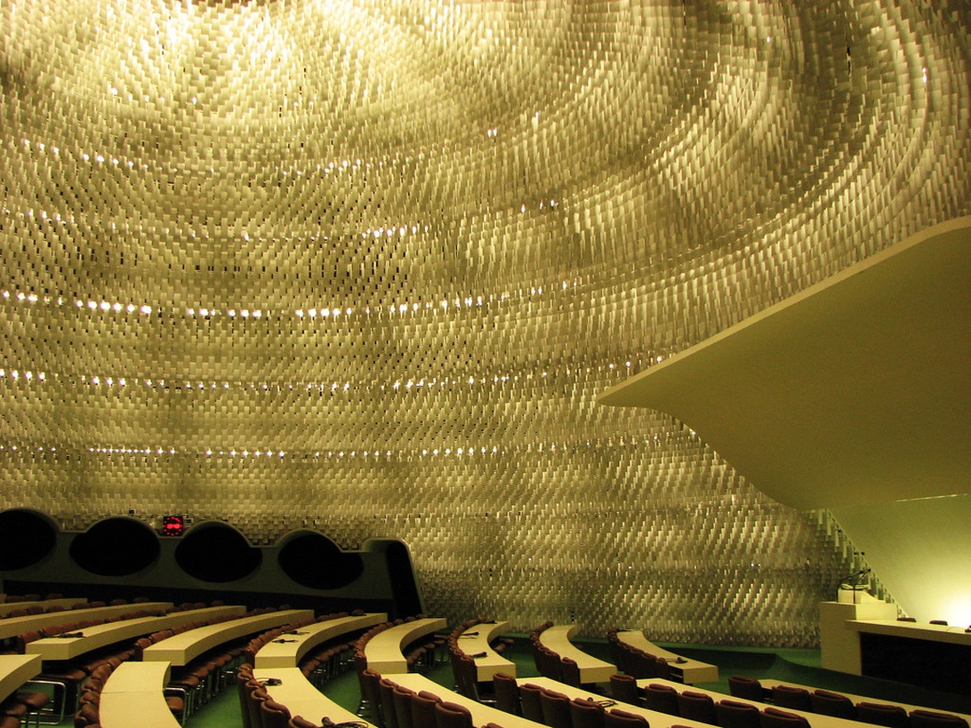 Grand auditorium avec des panneaux acoustiques dorés et incurvés sur les murs et le plafond, illustrant un design acoustique sophistiqué.